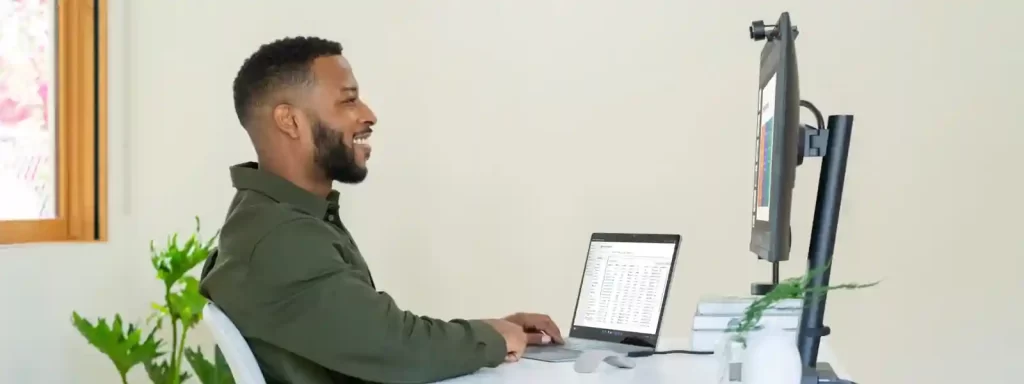 MSFT Man sitting at desk using a Surface device connected to a separate monitor